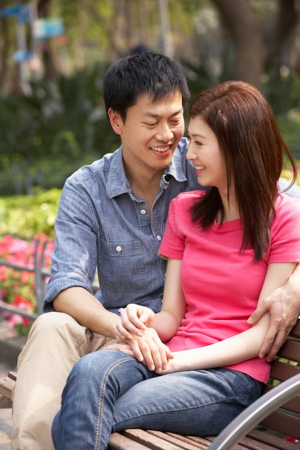 Junge chinesische Paare, die auf Park-Bank sich entspannen stockfotografie Junge chinesische Paare, die auf Park-Bank sich entspannen stockfotografie