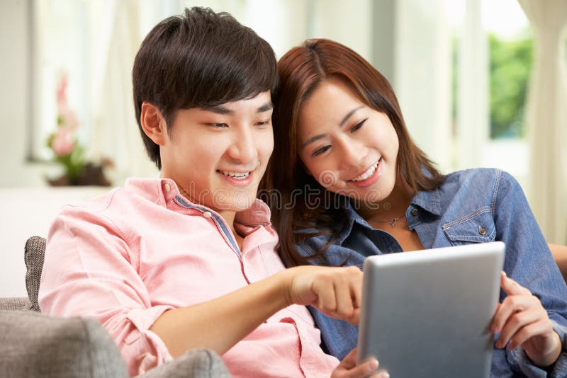 Junge chinesische Paare unter Verwendung der Digital-Tablette lizenzfreie stockfotos Junge chinesische Paare unter Verwendung der Digital-Tablette lizenzfreie stockfotos