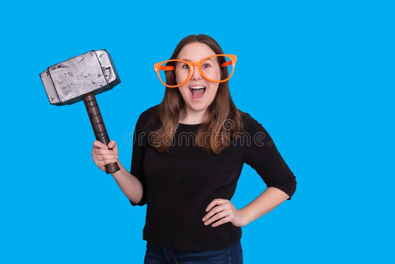Junge Dame, die eine Gummiholzhammerhammer-Fotostütze und großes orange ein Glaspassfotoautomatporträt hält