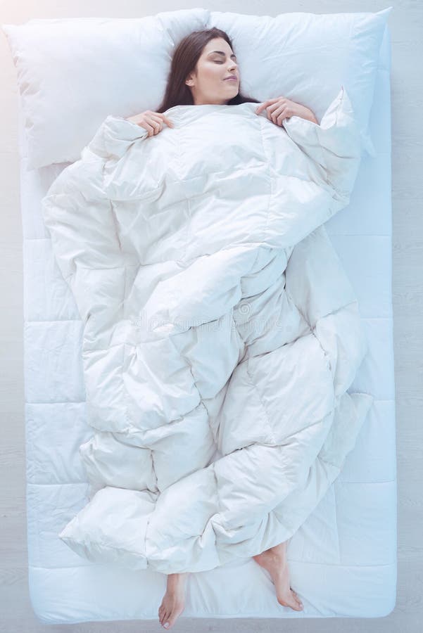 Junge Dame, die im Bett mit Daunendecke vorbei schläft stockbilder Junge Dame, die im Bett mit Daunendecke vorbei schläft stockbilder