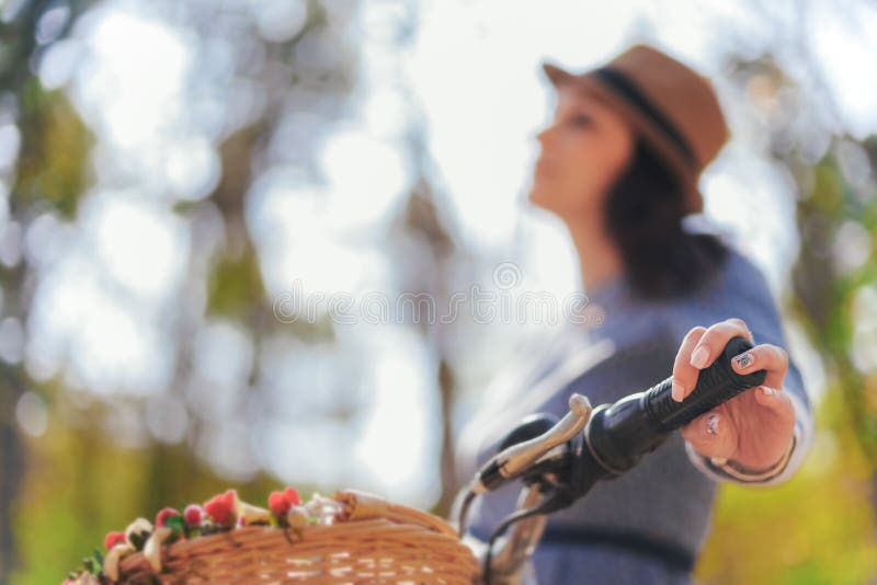 Junge Dame in einem Hut, in einem Park mit ihrem Weinlesefahrrad lizenzfreies stockbild Junge Dame in einem Hut, in einem Park mit ihrem Weinlesefahrrad lizenzfreies stockbild