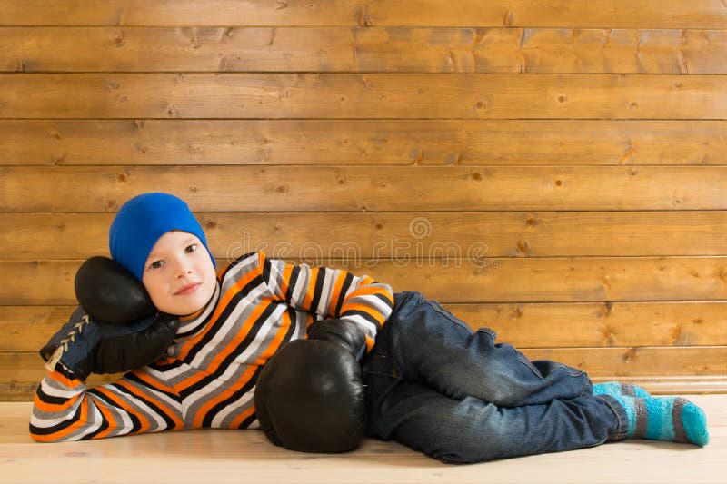 Junge in den alten Handschuhen für das Boxen, stehend auf dem Bretterboden still stockbild Junge in den alten Handschuhen für das Boxen, stehend auf dem Bretterboden still stockbild