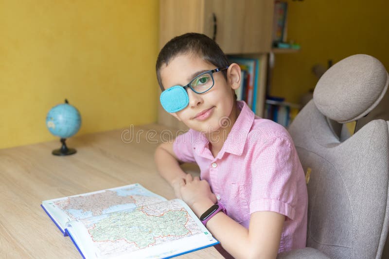 Junge in den Gläser mit Patches Hausaufgaben mit Buch Prüfung. Quarantäne. Fernunterricht. Fernausbildung. fauler Amblyopia Auge d stockbilder