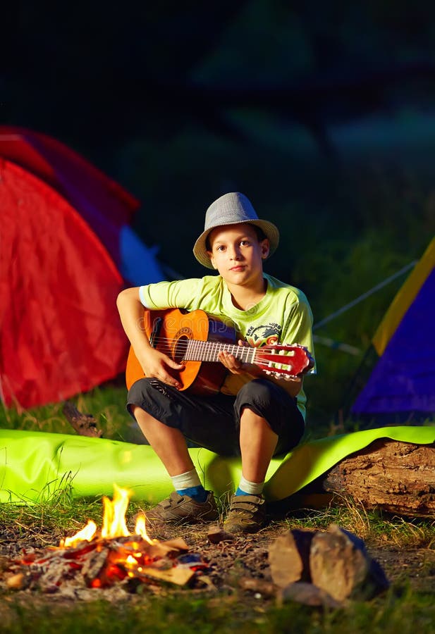 Junge, der eine Gitarre, Sommerlager spielt stockbild Junge, der eine Gitarre, Sommerlager spielt stockbild