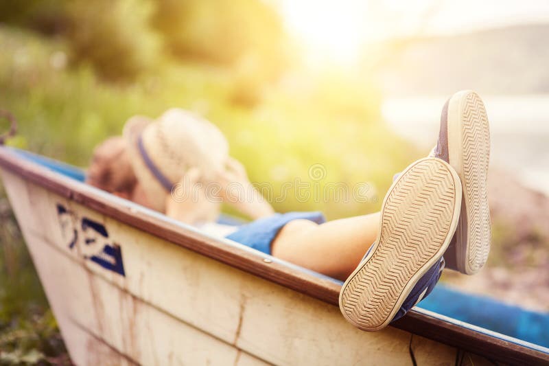 Junge, der im alten Boot im Seeküstenabschluß herauf Bild liegt lizenzfreie stockbilder Junge, der im alten Boot im Seeküstenabschluß herauf Bild liegt lizenzfreie stockbilder