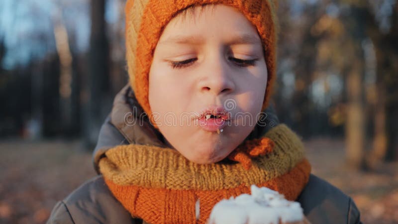 Junge, der im Herbstpark einen süßen Kuchen isst.