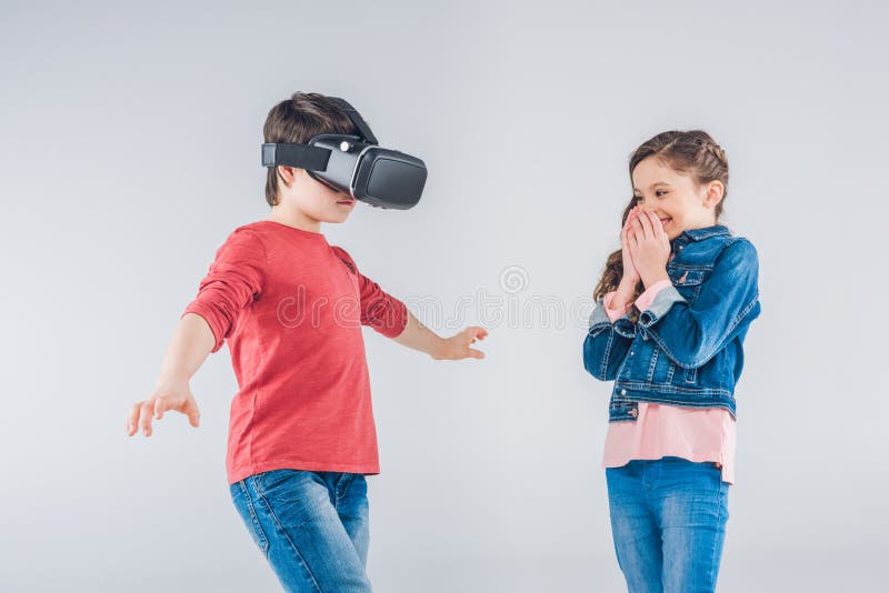 Junge, der Kopfhörer der virtuellen Realität während Mädchen schaut auf ihm verwendet stockfotos Junge, der Kopfhörer der virtuellen Realität während Mädchen schaut auf ihm verwendet stockfotos