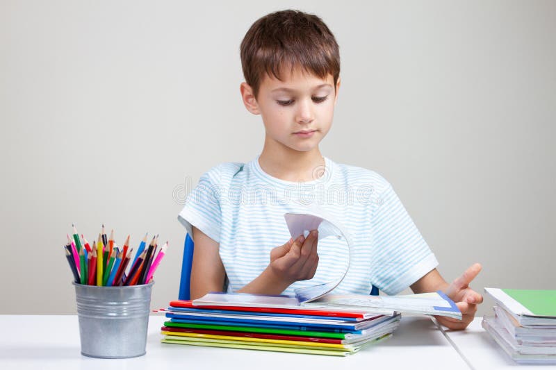 Junge, der am Schreibtisch mit Stapel von Schulbüchern und von Notizbüchern sitzt und zu Hause Hausarbeit tut lizenzfreie stockfotografie Junge, der am Schreibtisch mit Stapel von Schulbüchern und von Notizbüchern sitzt und zu Hause Hausarbeit tut lizenzfreie stockfotografie