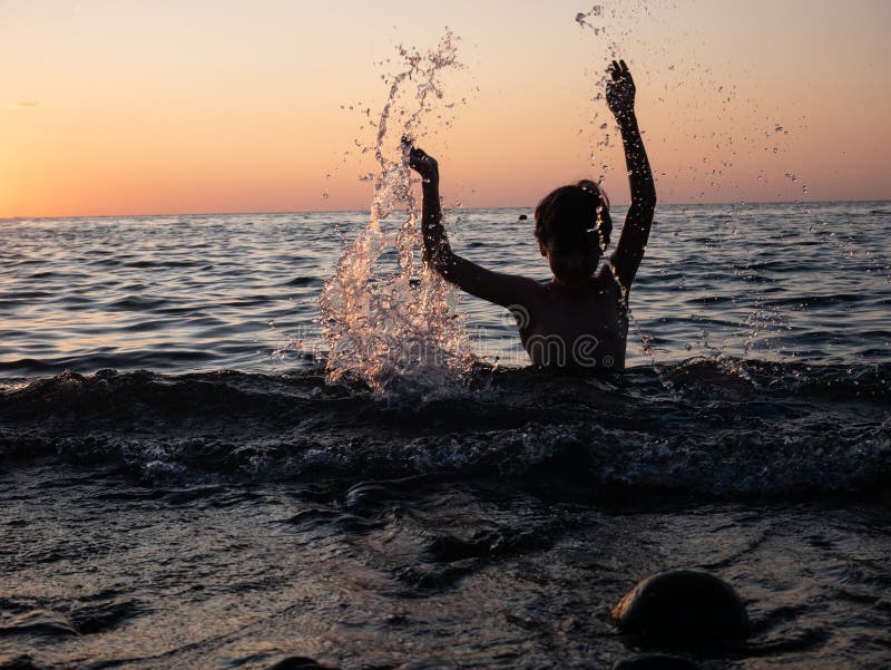 Junge, die im Meer mit aufgezogenen Armen plündert Kinderspiel lizenzfreie stockbilder Junge, die im Meer mit aufgezogenen Armen plündert Kinderspiel lizenzfreie stockbilder