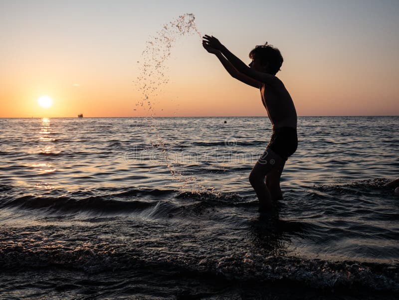 Junge, die im Meer mit aufgezogenen Armen plündert Kinderspiel stockbilder Junge, die im Meer mit aufgezogenen Armen plündert Kinderspiel stockbilder
