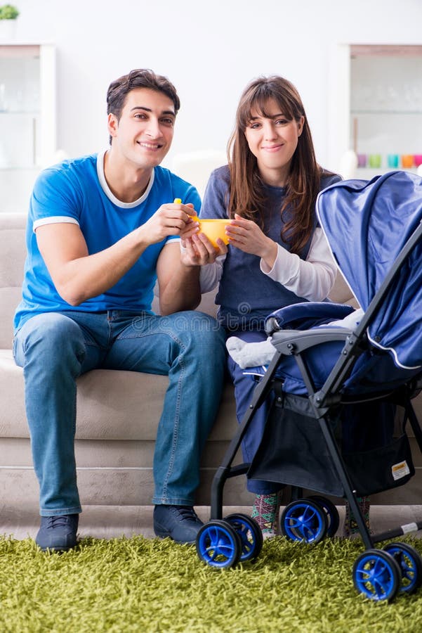 Junge Eltern mit ihrem neugeborenen Baby in Baby Pram, der auf Th sitzt lizenzfreie stockfotos Junge Eltern mit ihrem neugeborenen Baby in Baby Pram, der auf Th sitzt lizenzfreie stockfotos
