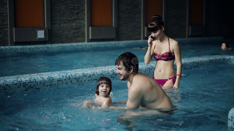 Junge Familie im Pool seinen Sohn unterrichtend zu schwimmen Ein Junge springt in das Wasser