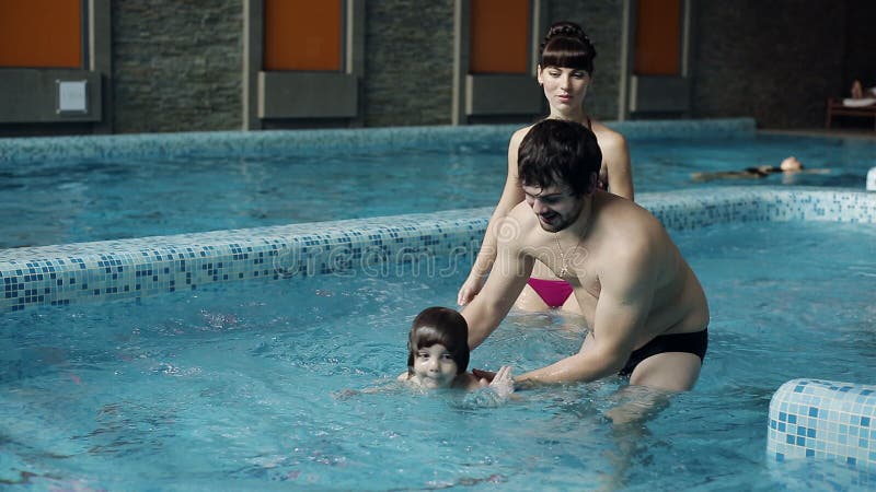 Junge Familie im Pool seinen Sohn unterrichtend zu schwimmen Ein Junge springt in das Wasser