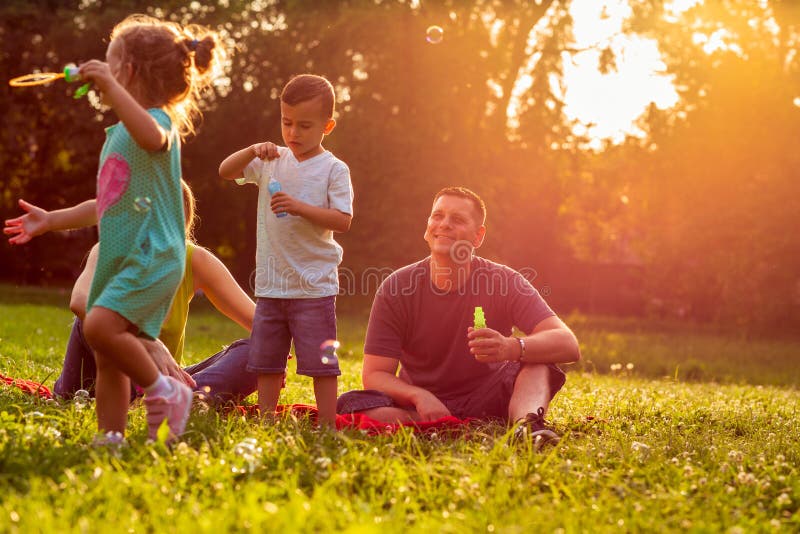 Junge Familie mit den Kindern, die Spaß in der Natur bei Sonnenuntergang haben stockbild Junge Familie mit den Kindern, die Spaß in der Natur bei Sonnenuntergang haben stockbild