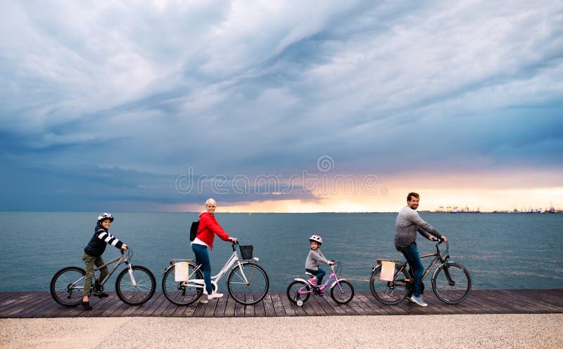 Junge Familie mit kleinen Kindern und Fahrrädern draußen auf Strand lizenzfreie stockbilder Junge Familie mit kleinen Kindern und Fahrrädern draußen auf Strand lizenzfreie stockbilder