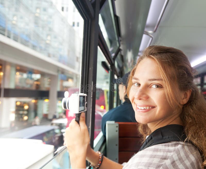 Junge Frau auf der Kamera vom Fenster des Touristenbusses lizenzfreie stockfotos Junge Frau auf der Kamera vom Fenster des Touristenbusses lizenzfreie stockfotos