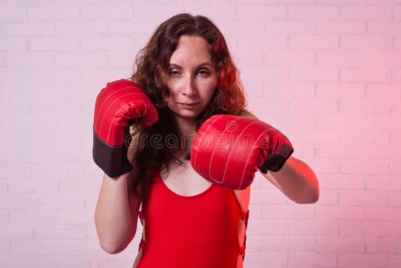 Junge Frau in den roten Boxhandschuhen auf einem rosa Hintergrund lizenzfreies stockbild Junge Frau in den roten Boxhandschuhen auf einem rosa Hintergrund lizenzfreies stockbild