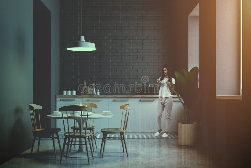 Junge Frau in der grauen Ziegelsteinküche und in Esszimmer lizenzfreies stockfoto