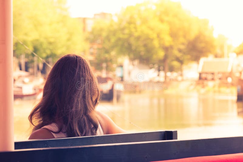 Junge Frau, die auf einer Bank aufpasst das Dock der Bucht an s sitzt stockbilder Junge Frau, die auf einer Bank aufpasst das Dock der Bucht an s sitzt stockbilder