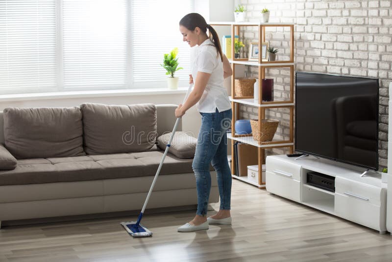 Junge Frau, die den Massivholzboden säubert stockfotografie