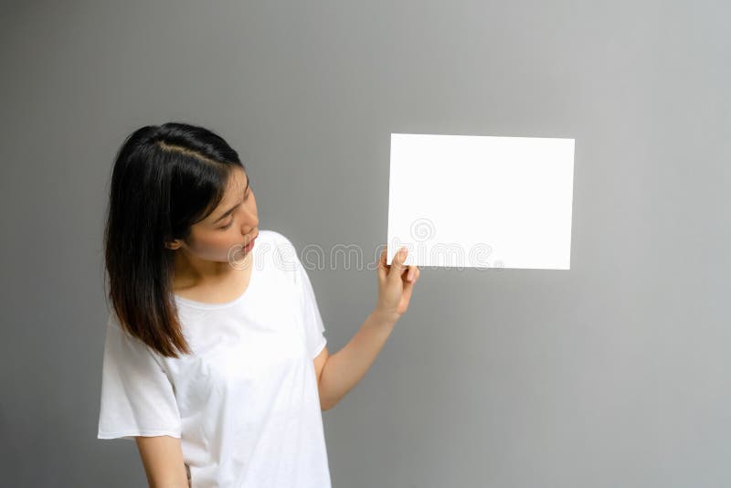 Junge Frau, die ein leeres Plakat f?r Text auf einem wei?en Hintergrund h?lt lizenzfreies stockfoto Junge Frau, die ein leeres Plakat f?r Text auf einem wei?en Hintergrund h?lt lizenzfreies stockfoto