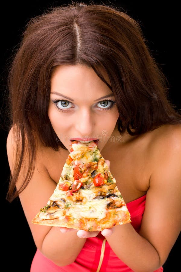 Young woman eating a piece of pizza against a black background. Young woman eating a piece of pizza against a black background
