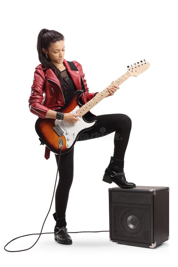 Junge Frau, die eine Bass-Gitarre spielt und nahe bei einem Verstärker steht