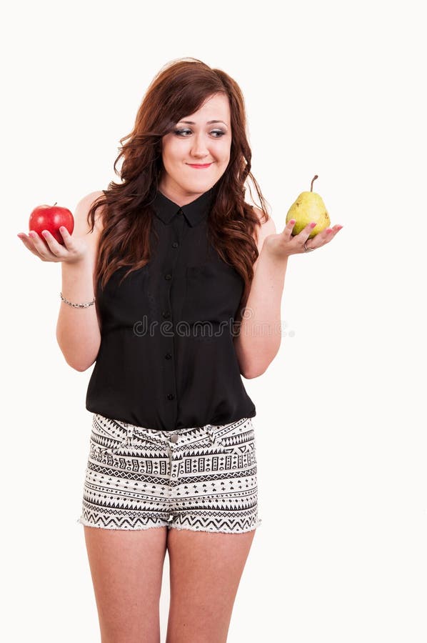 Young woman comparing apple and a pear, trying to decide which one to choose. Young woman comparing apple and a pear, trying to decide which one to choose