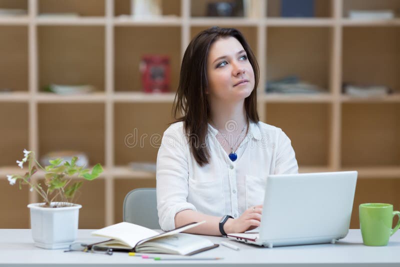Junge Frau, die in entspannter Lage am Arbeitsplatz denkt stockfoto Junge Frau, die in entspannter Lage am Arbeitsplatz denkt stockfoto