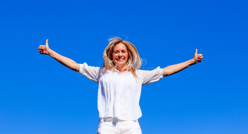 Junge Frau, die gegen blauen Himmel springt stockfotografie Junge Frau, die gegen blauen Himmel springt stockfotografie
