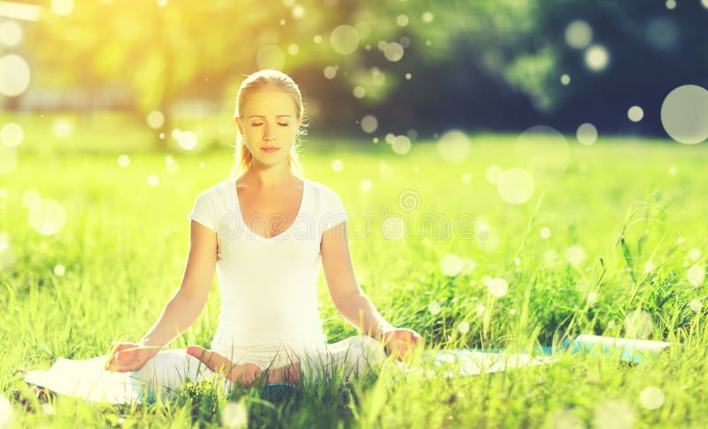 Junge Frau, die Meditation und Yoga auf grünem Gras im summe genießt stockfotos