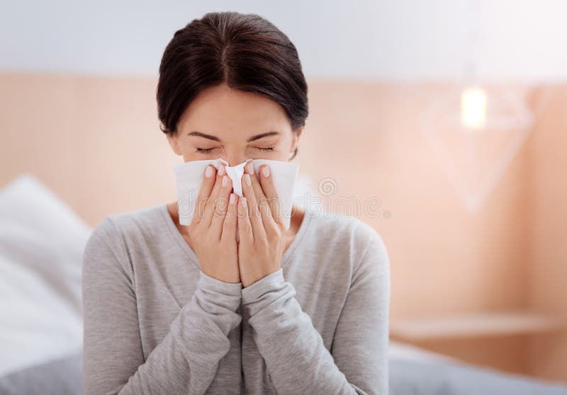 Junge Frau, die mit ihren Augen geschlossen niest lizenzfreie stockbilder