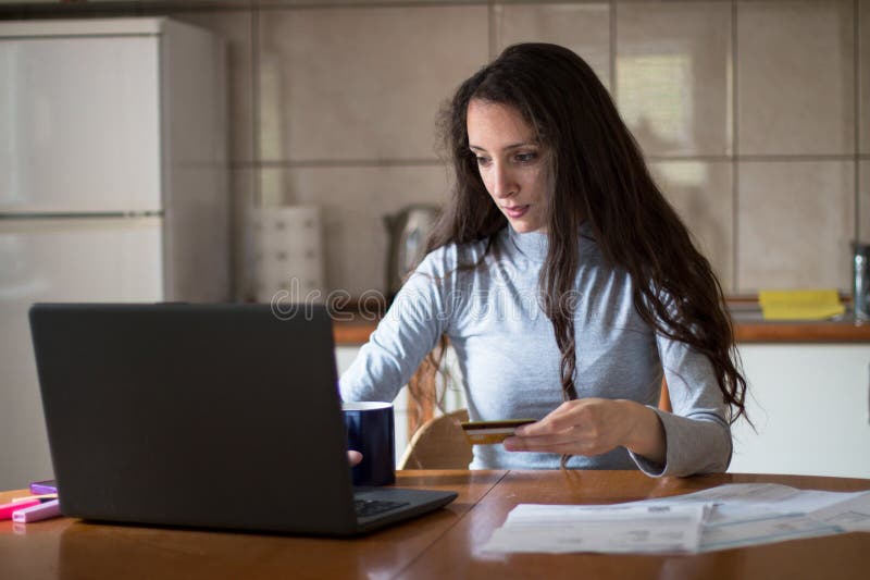 Junge Frau, die Rechnungen mit Debitkarte von zu Hause bezahlt lizenzfreies stockfoto
