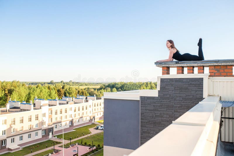 Junge Frau, die Yoga auf dem Dach tut lizenzfreie stockbilder Junge Frau, die Yoga auf dem Dach tut lizenzfreie stockbilder