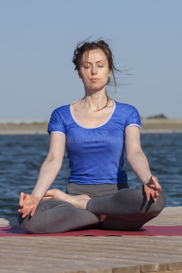 Young woman exercising yoga pose by the lake shore at sunset, girl in headstand yoga pose. People travel relaxation concept. Portrait. Young woman exercising yoga pose by the lake shore at sunset, girl in headstand yoga pose. People travel relaxation concept. Portrait