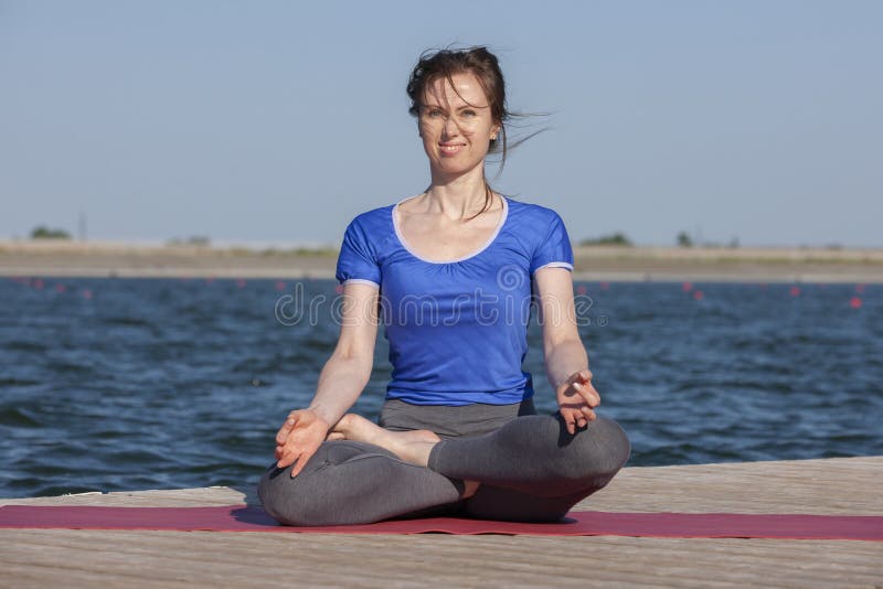 Young woman exercising yoga pose by the lake shore at sunset, girl in headstand yoga pose. People travel relaxation concept. Portrait. Young woman exercising yoga pose by the lake shore at sunset, girl in headstand yoga pose. People travel relaxation concept. Portrait