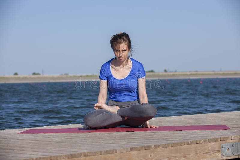 Young woman exercising yoga pose by the lake shore at sunset, girl in headstand yoga pose. People travel relaxation concept. Portrait. Young woman exercising yoga pose by the lake shore at sunset, girl in headstand yoga pose. People travel relaxation concept. Portrait