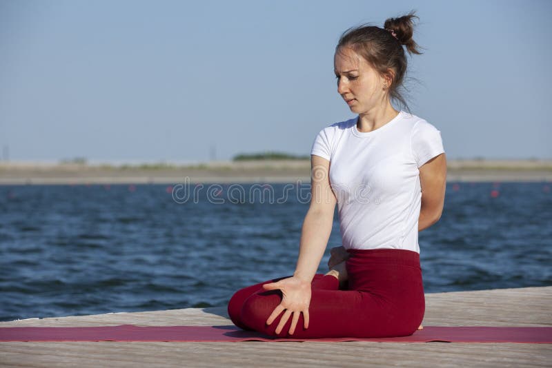 Young woman exercising yoga pose by the lake shore at sunset, girl in headstand yoga pose. People travel relaxation concept. Portrait. Young woman exercising yoga pose by the lake shore at sunset, girl in headstand yoga pose. People travel relaxation concept. Portrait