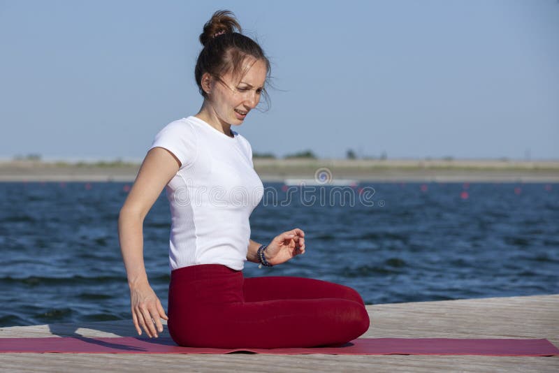 Young woman exercising yoga pose by the lake shore at sunset, girl in headstand yoga pose. People travel relaxation concept. Portrait. Young woman exercising yoga pose by the lake shore at sunset, girl in headstand yoga pose. People travel relaxation concept. Portrait