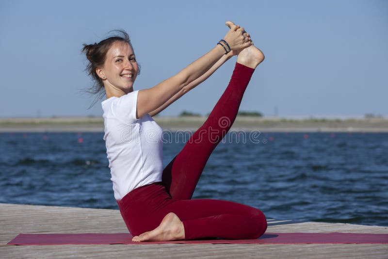 Young woman exercising yoga pose by the lake shore at sunset, girl in headstand yoga pose. People travel relaxation concept. Portrait. Young woman exercising yoga pose by the lake shore at sunset, girl in headstand yoga pose. People travel relaxation concept. Portrait