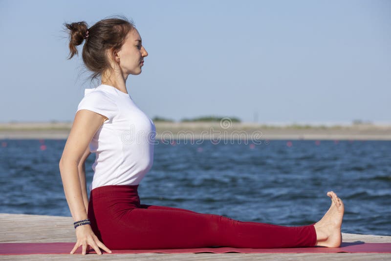 Young woman exercising yoga pose by the lake shore at sunset, girl in headstand yoga pose. People travel relaxation concept. Portrait. Young woman exercising yoga pose by the lake shore at sunset, girl in headstand yoga pose. People travel relaxation concept. Portrait