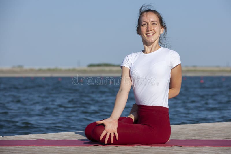 Young woman exercising yoga pose by the lake shore at sunset, girl in headstand yoga pose. People travel relaxation concept. Portrait. Young woman exercising yoga pose by the lake shore at sunset, girl in headstand yoga pose. People travel relaxation concept. Portrait