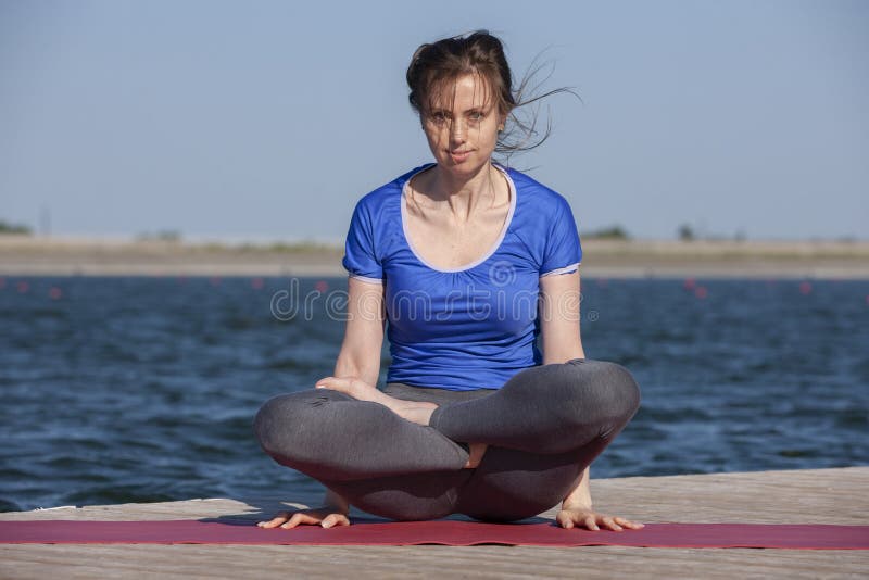 Young woman exercising yoga pose by the lake shore at sunset, girl in headstand yoga pose. People travel relaxation concept. Portrait. Young woman exercising yoga pose by the lake shore at sunset, girl in headstand yoga pose. People travel relaxation concept. Portrait