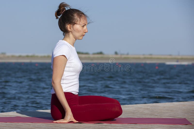 Young woman exercising yoga pose by the lake shore at sunset, girl in headstand yoga pose. People travel relaxation concept. Portrait. Young woman exercising yoga pose by the lake shore at sunset, girl in headstand yoga pose. People travel relaxation concept. Portrait