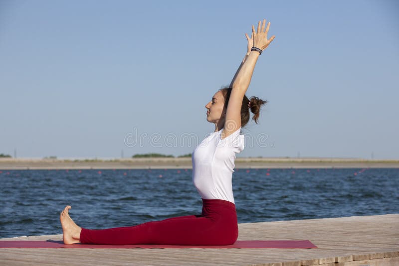 Young woman exercising yoga pose by the lake shore at sunset, girl in headstand yoga pose. People travel relaxation concept. Portrait. Young woman exercising yoga pose by the lake shore at sunset, girl in headstand yoga pose. People travel relaxation concept. Portrait