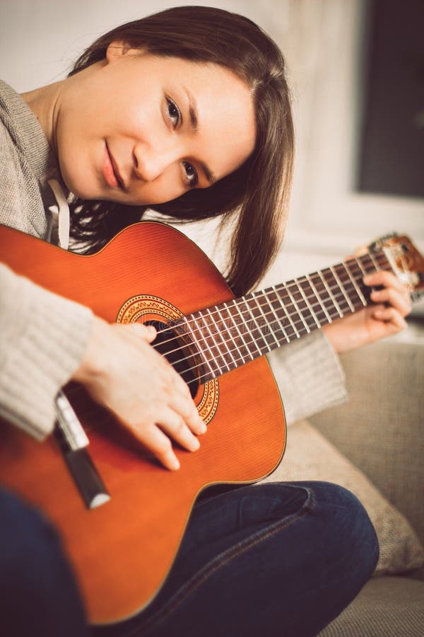 Junge Frau, die zu Hause Gitarre spielt Entspannte glückliche junge Frau mit Musikinstrumentporträt