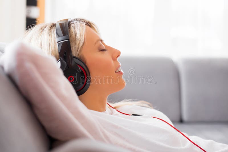 Junge Frau, die zu Hause Musik auf Kopfhörern hört