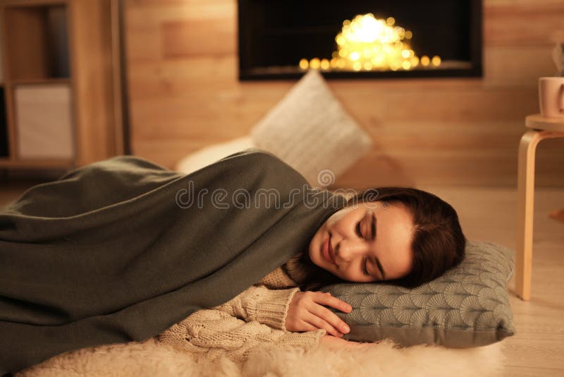 Junge Frau, die zu Hause nahe dekorativem Kamin schläft stockfoto Junge Frau, die zu Hause nahe dekorativem Kamin schläft stockfoto