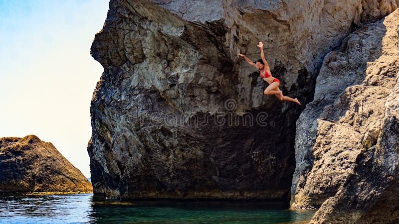 Junge Frau, die zum Meer von einer Klippe springt lizenzfreies stockfoto Junge Frau, die zum Meer von einer Klippe springt lizenzfreies stockfoto
