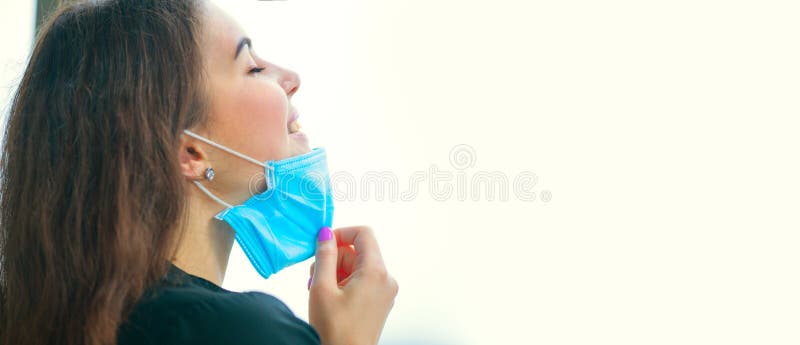 Junge Frau entfernt ihre Schutzmaske und atmt reine Luft ein Coronavirus, Virenschutz Grippe Covid -19